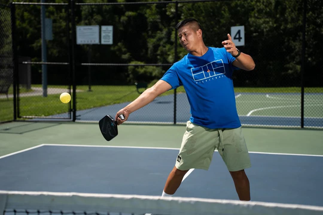 Sam Morris reaching toward a yellow pickleball with his paddle.