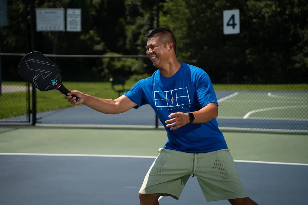 Sam Morris smiling while extending his paddle over the court.