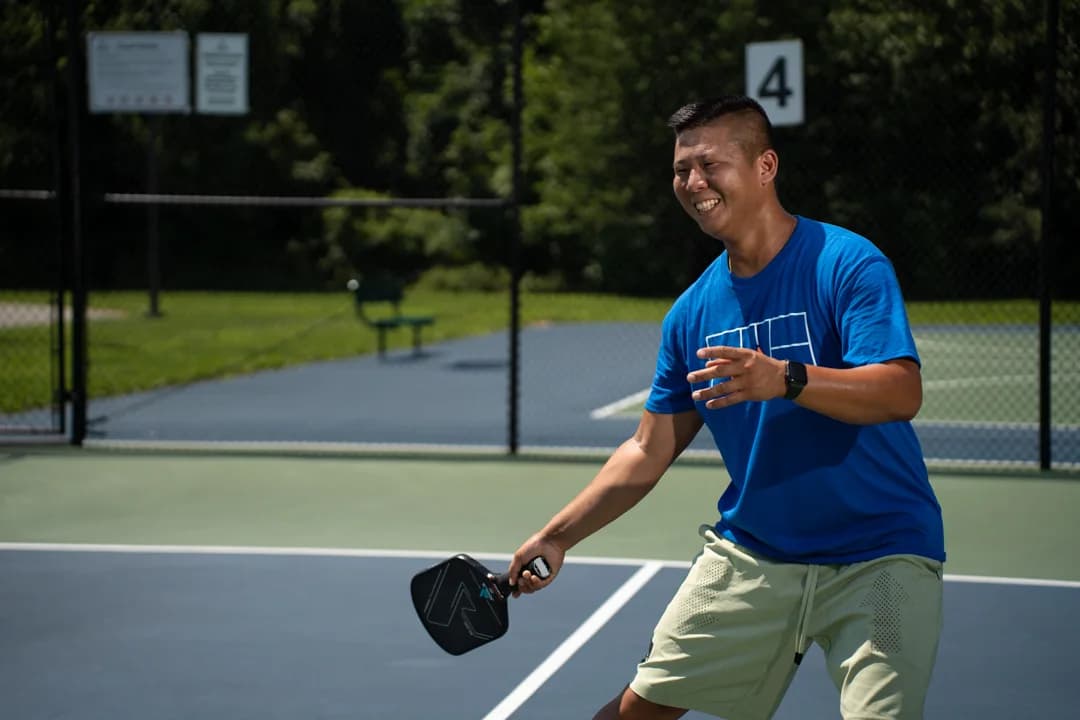 Sam Morris smiling with his paddle held low on an outdoor court.