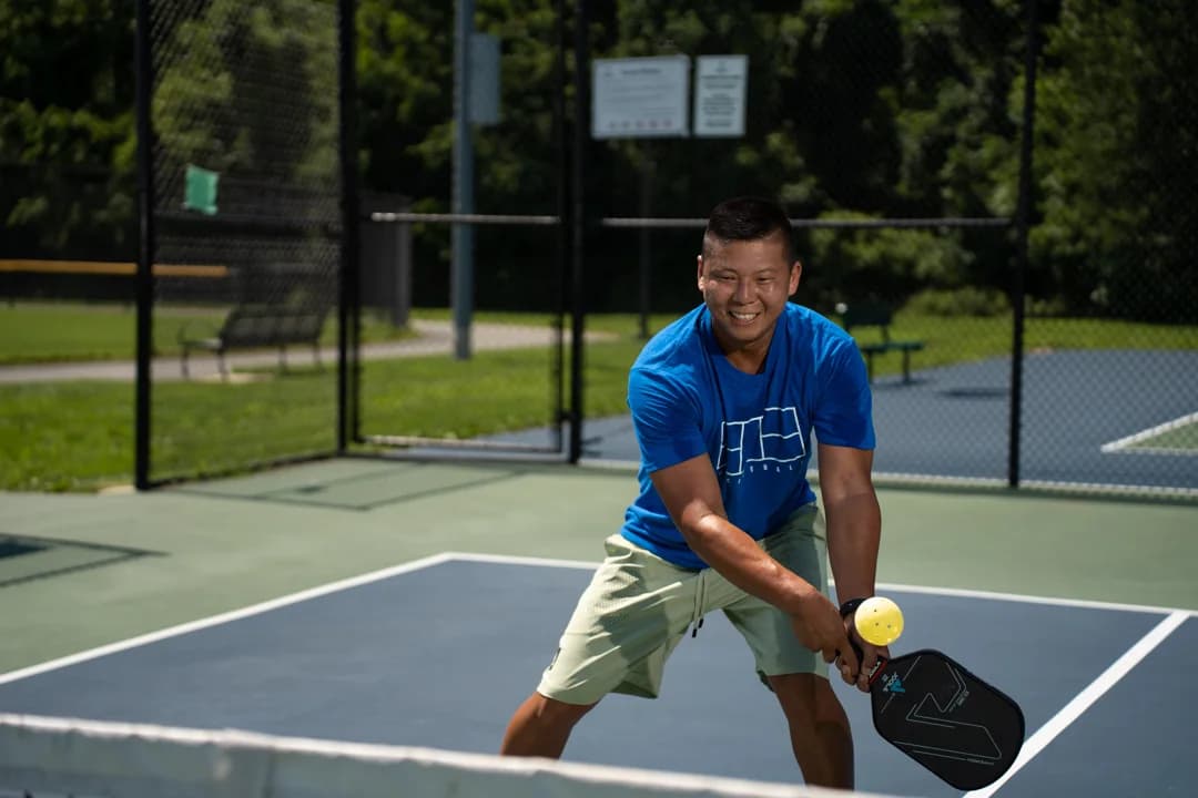 Sam Morris lowering his paddle toward a yellow ball in a wide stance.
