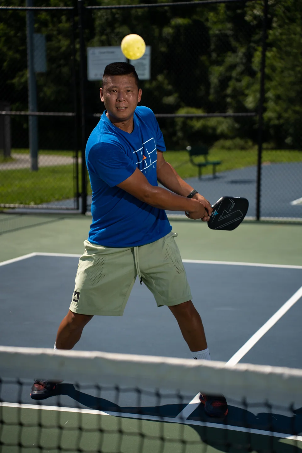 Sam Morris tracking a yellow ball while preparing a two-handed backhand.
