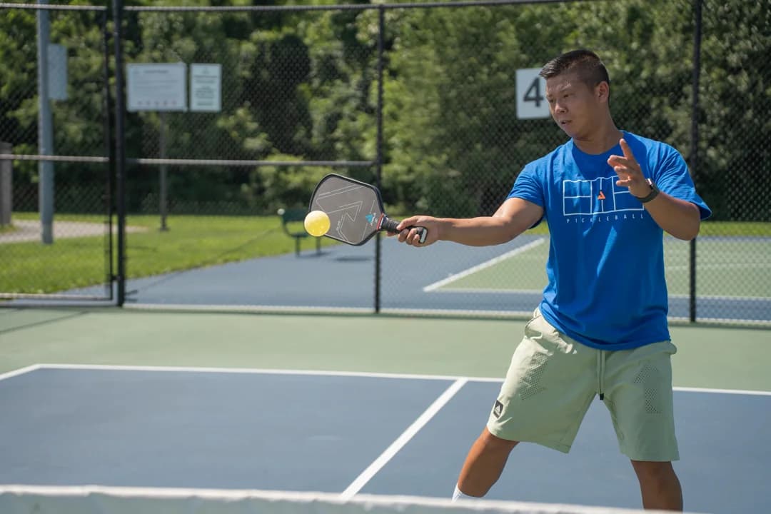 Sam Morris meeting a yellow ball with a forehand on an outdoor court.