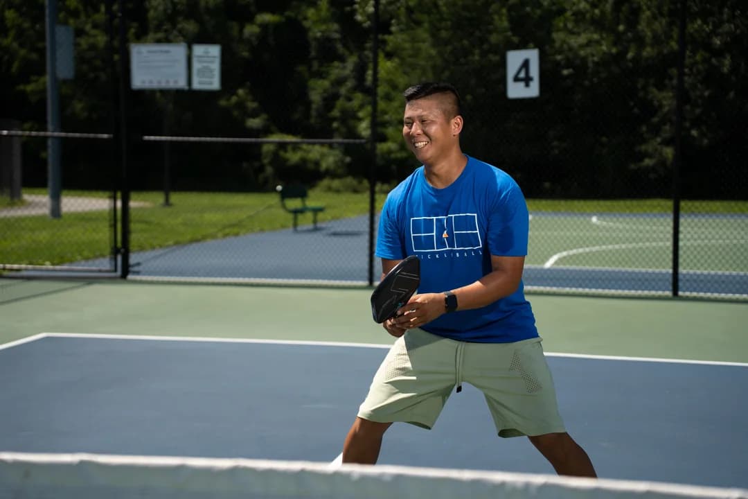 Sam Morris holding his paddle ready and smiling across an outdoor court.